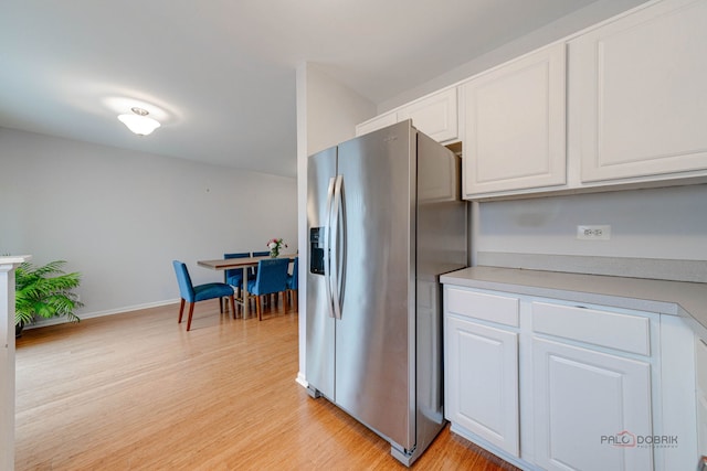 4553 W Hill Ave Unit 3, Waukegan, IL 60085 - kitchen with stainless steel refrigerator with ice dispenser, white cabinetry, light wood-style floors, and light countertops