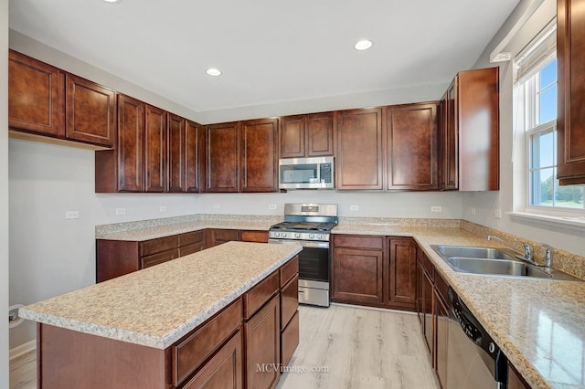 kitchen with stainless steel appliances, a sink, light countertops, light wood-type flooring, and recessed lighting
