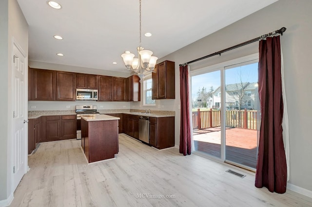 kitchen with stainless steel appliances, light wood-style floors, a sink, a kitchen island, and recessed lighting