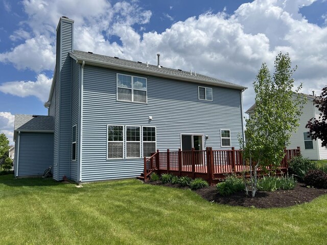 back of house featuring a wooden deck, a chimney, and a yard