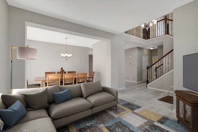 living area featuring a chandelier, stairway, wood finished floors, and baseboards