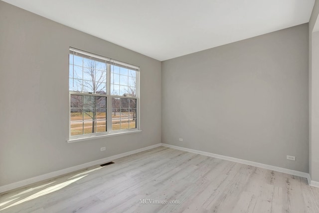 empty room featuring light wood finished floors and baseboards