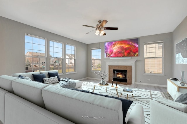 living room featuring baseboards, a ceiling fan, wood finished floors, and a tiled fireplace