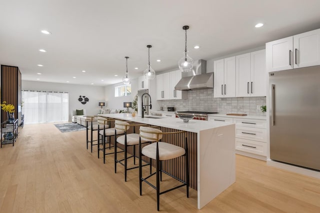 1522 W Wolfram St, Chicago, IL 60657 - kitchen with wall chimney range hood, appliances with stainless steel finishes, white cabinets, and a kitchen island with sink