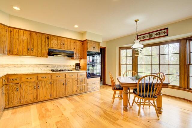 809 S Charles Ave, Naperville, IL 60540 - kitchen featuring brown cabinetry, backsplash, light wood-type flooring, black appliances, and under cabinet range hood