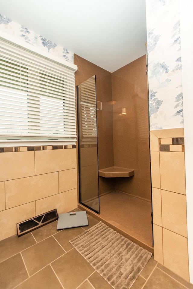 full bath featuring tile walls, a wainscoted wall, visible vents, walk in shower, and tile patterned floors