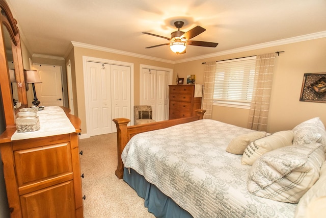 bedroom with light colored carpet, a ceiling fan, ornamental molding, and multiple closets
