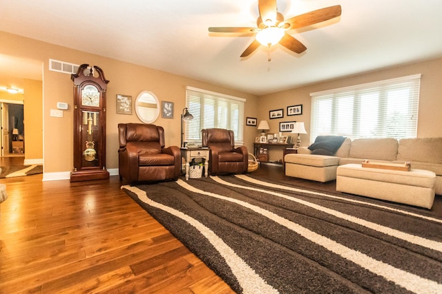 living room featuring baseboards, visible vents, a ceiling fan, and wood finished floors