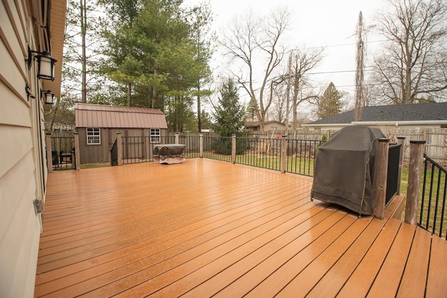 wooden terrace featuring fence, a shed, area for grilling, and an outdoor structure