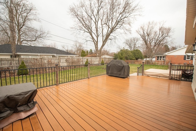 wooden terrace with a grill, a lawn, and a fenced backyard