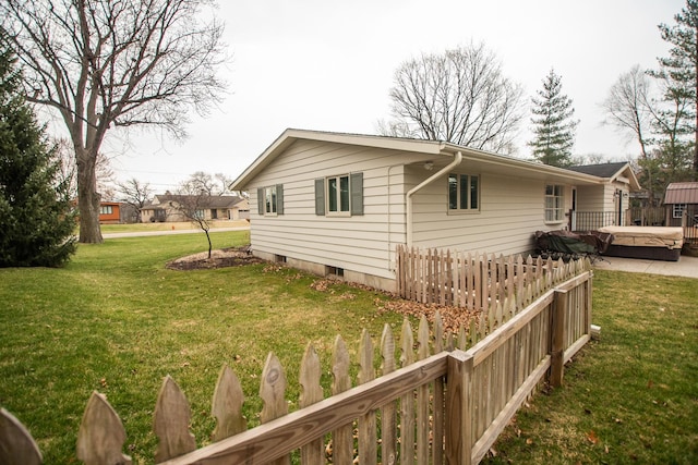 view of side of home with fence and a lawn