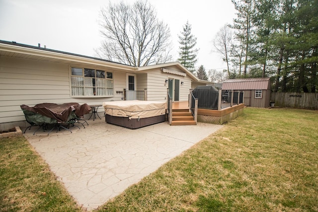 rear view of property featuring a wooden deck, fence, a hot tub, a patio, and a lawn