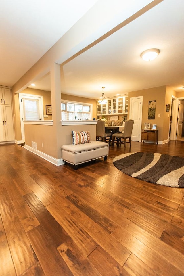 living room featuring baseboards, a notable chandelier, and hardwood / wood-style flooring