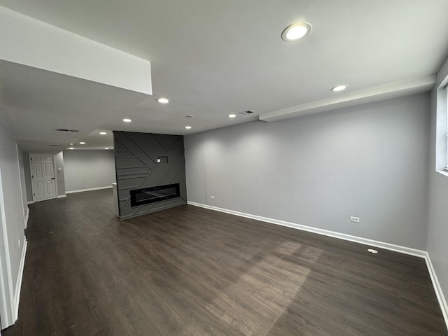 unfurnished living room with a fireplace, dark wood-style floors, baseboards, and recessed lighting