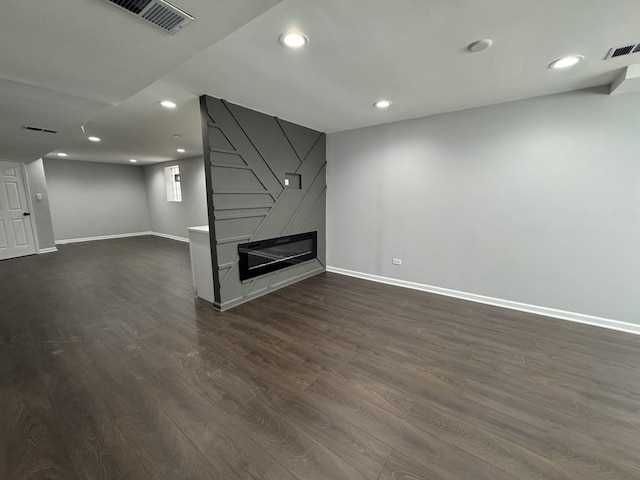 below grade area with recessed lighting, visible vents, a large fireplace, and dark wood-type flooring