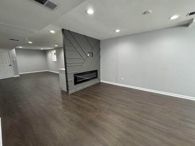 unfurnished living room featuring dark wood-style flooring, recessed lighting, a fireplace, and visible vents
