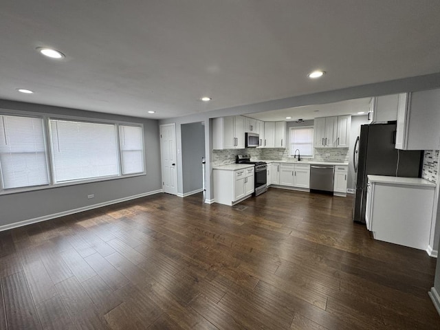 kitchen with light countertops, plenty of natural light, dark wood finished floors, tasteful backsplash, and appliances with stainless steel finishes