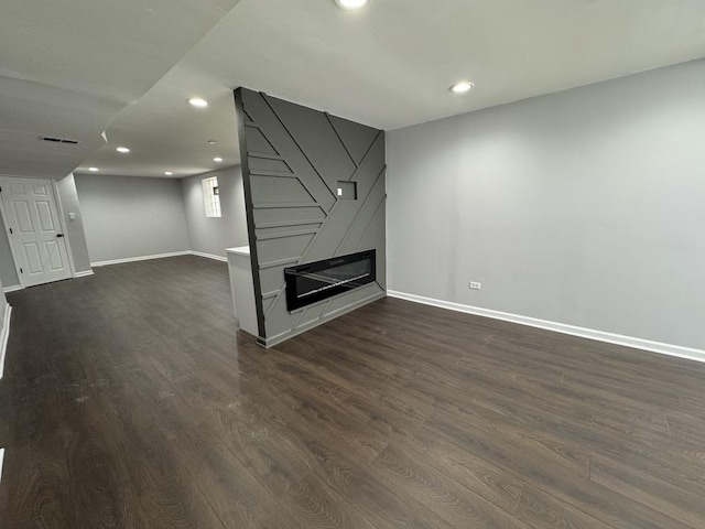 basement with dark wood-type flooring, a fireplace, baseboards, and recessed lighting
