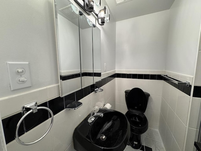 half bathroom with tile walls, a sink, and toilet