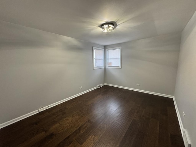 empty room featuring dark wood-style floors and baseboards