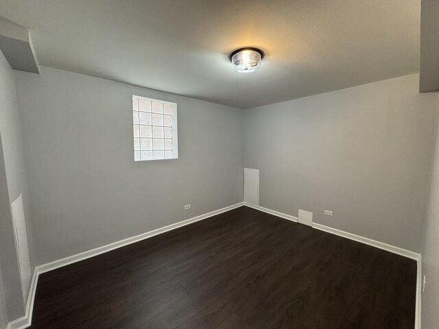 spare room with dark wood-style flooring and baseboards