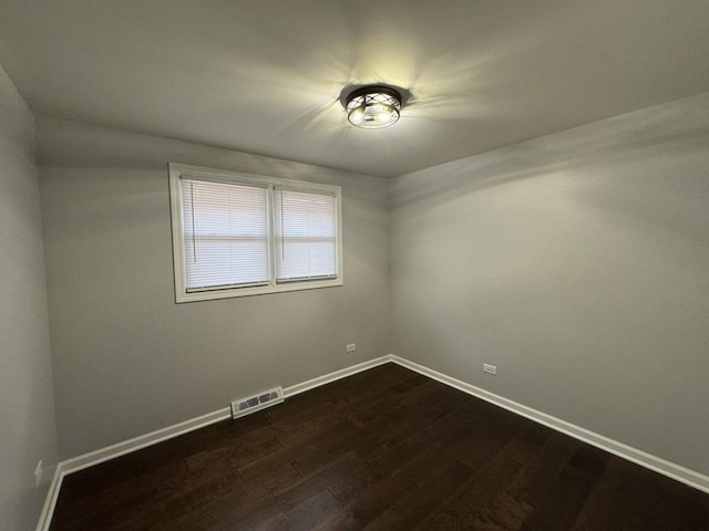 unfurnished room with dark wood-type flooring, baseboards, and visible vents