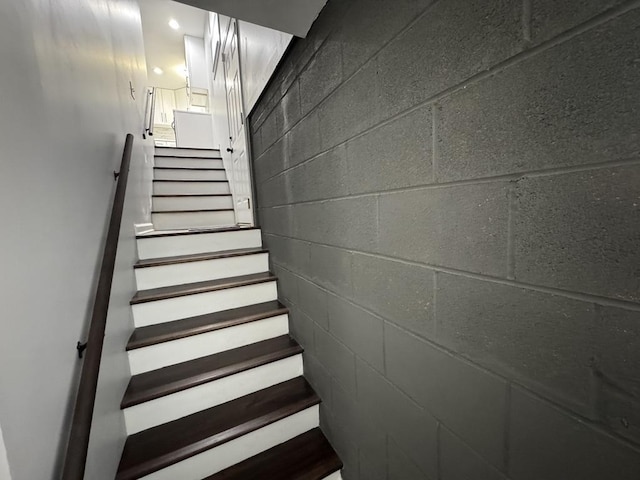 staircase featuring concrete block wall