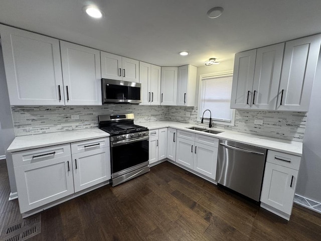 kitchen with white cabinetry, dark wood-style flooring, a sink, and stainless steel appliances
