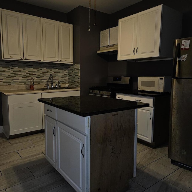2251 S Kirkland Ave, Chicago, IL 60623 - kitchen with gas stove, under cabinet range hood, a sink, white microwave, and freestanding refrigerator