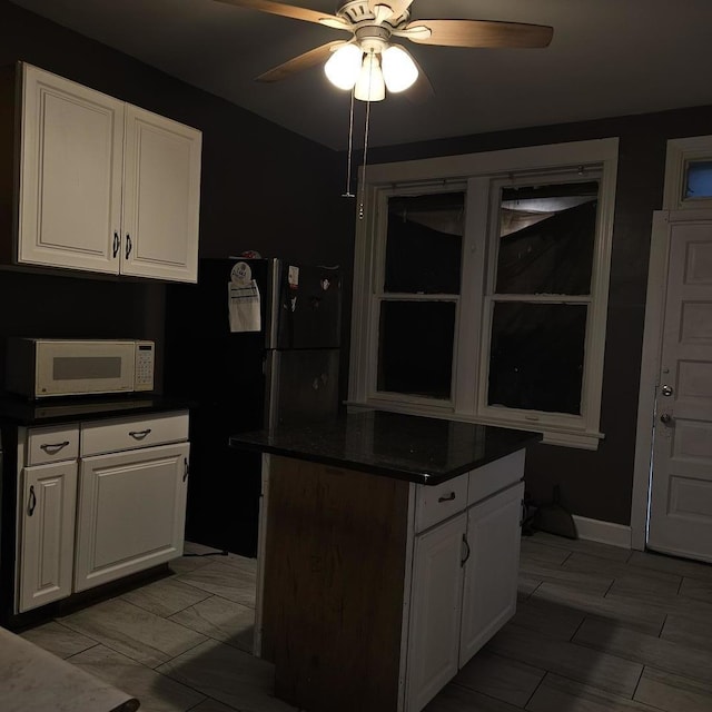 2251 S Kirkland Ave, Chicago, IL 60623 - kitchen with a kitchen island, dark countertops, ceiling fan, white cabinets, and white microwave