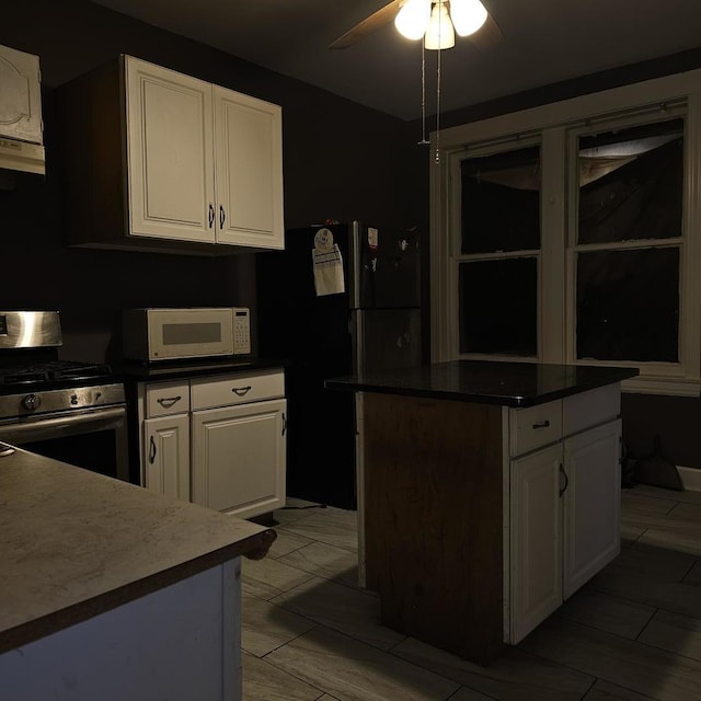 2251 S Kirkland Ave, Chicago, IL 60623 - kitchen featuring white cabinets, ceiling fan, white microwave, stainless steel gas stove, and freestanding refrigerator