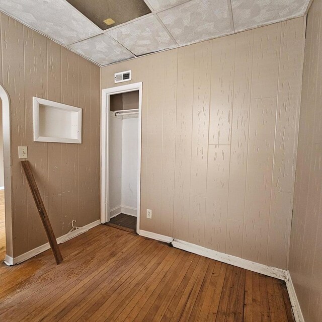 2251 S Kirkland Ave, Chicago, IL 60623 - unfurnished bedroom with baseboards, visible vents, wood walls, and hardwood / wood-style flooring