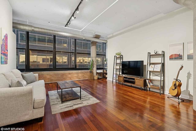 living area with track lighting, baseboards, and wood finished floors