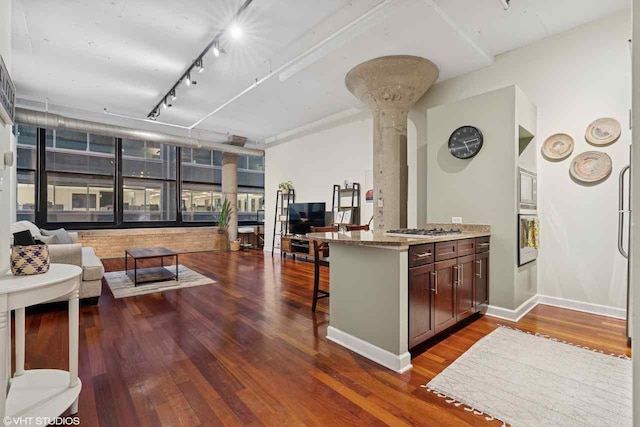 kitchen featuring dark wood-style flooring, appliances with stainless steel finishes, a breakfast bar, open floor plan, and decorative columns