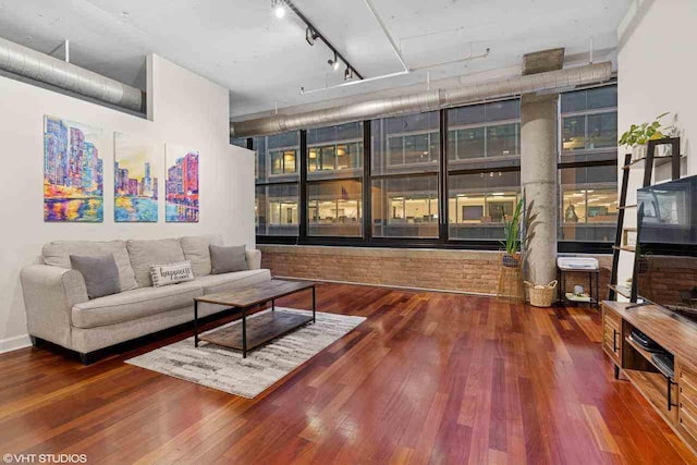 living room featuring wood-type flooring, track lighting, and a towering ceiling