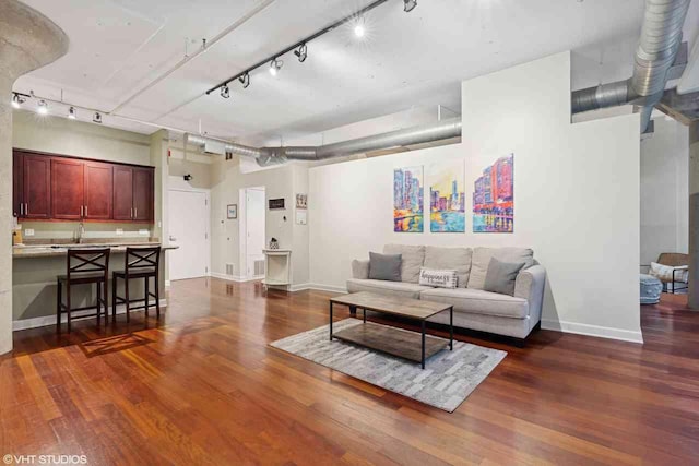 living room with rail lighting, baseboards, and dark wood-type flooring
