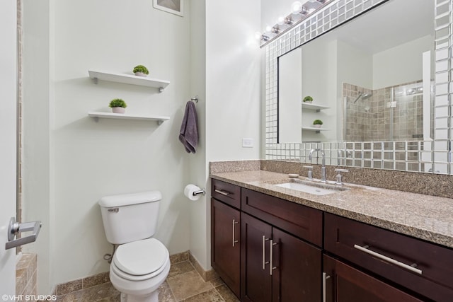 bathroom featuring baseboards, vanity, toilet, and tiled shower