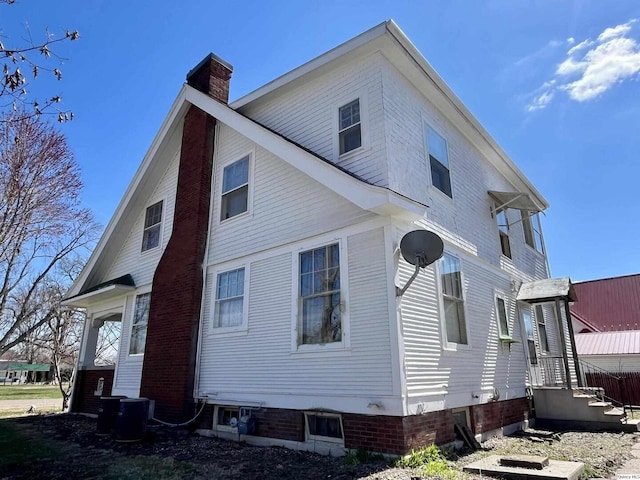 exterior space with central air condition unit and a chimney