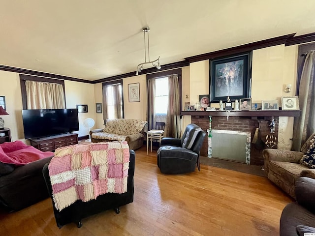 living room featuring a fireplace, ornamental molding, and wood finished floors