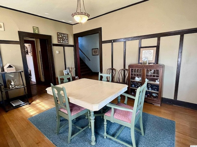 dining room featuring stairs, wood finished floors, and crown molding
