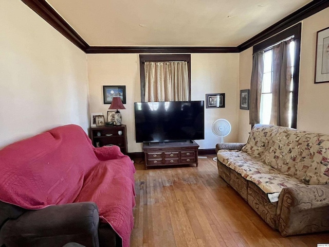living room featuring baseboards, ornamental molding, and wood-type flooring