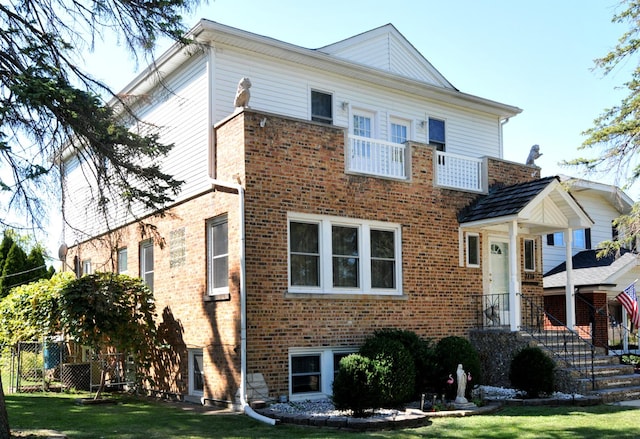 view of front facade with brick siding, fence, and a front lawn