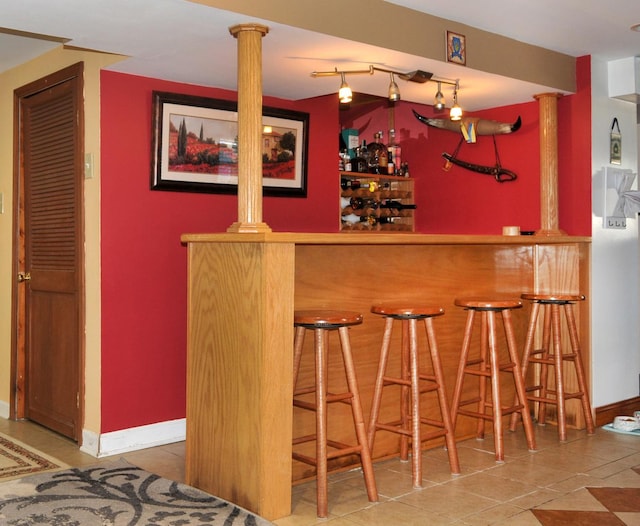 bar with a bar, baseboards, and tile patterned floors