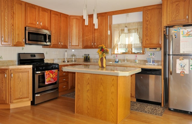 kitchen featuring light countertops, stainless steel appliances, backsplash, a kitchen island, and light wood-style floors