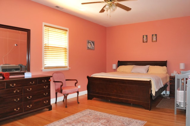 bedroom with baseboards, ceiling fan, visible vents, and light wood finished floors