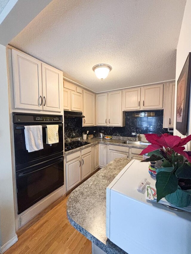 5500 Lincoln Ave Ave Unit 118E, Morton Grove, IL 60053 - kitchen featuring black appliances, light wood-type flooring, tasteful backsplash, and a textured ceiling