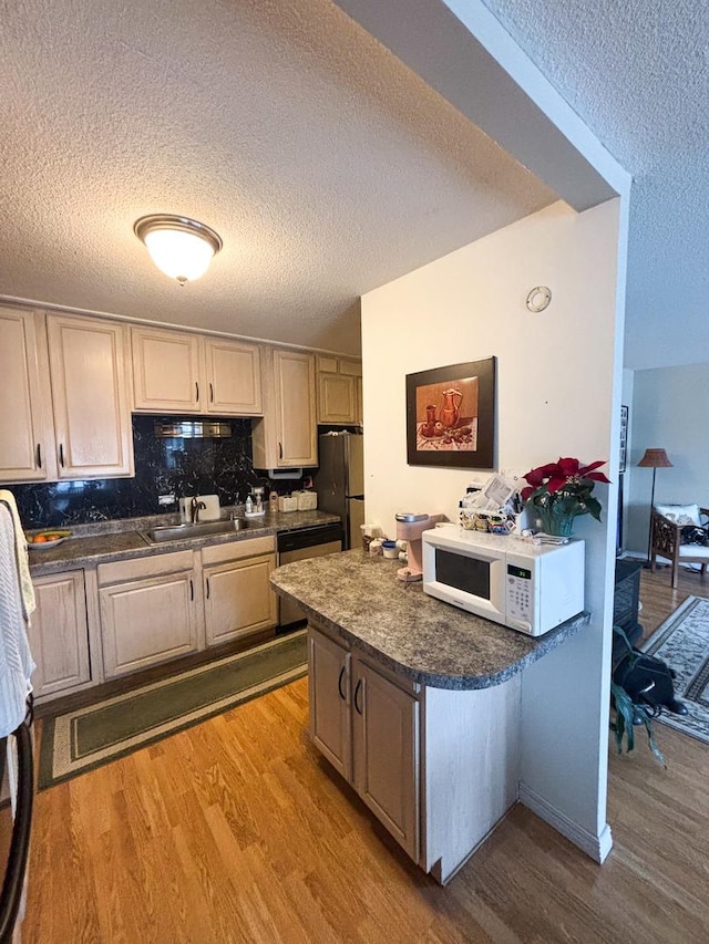 5500 Lincoln Ave Ave Unit 118E, Morton Grove, IL 60053 - kitchen featuring stainless steel appliances, wood finished floors, a textured ceiling, dark countertops, and backsplash