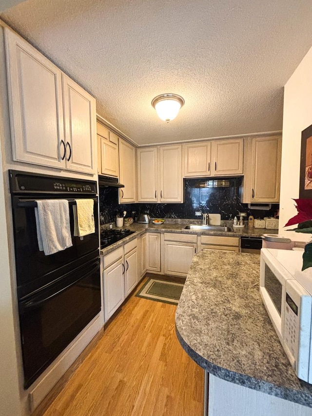 5500 Lincoln Ave Ave Unit 118E, Morton Grove, IL 60053 - kitchen featuring black appliances, light wood-style flooring, under cabinet range hood, backsplash, and a textured ceiling