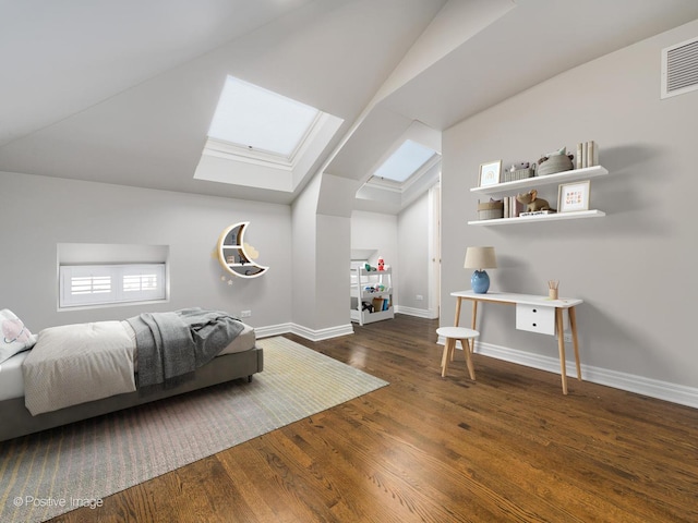 bedroom featuring baseboards, vaulted ceiling with skylight, visible vents, and wood finished floors