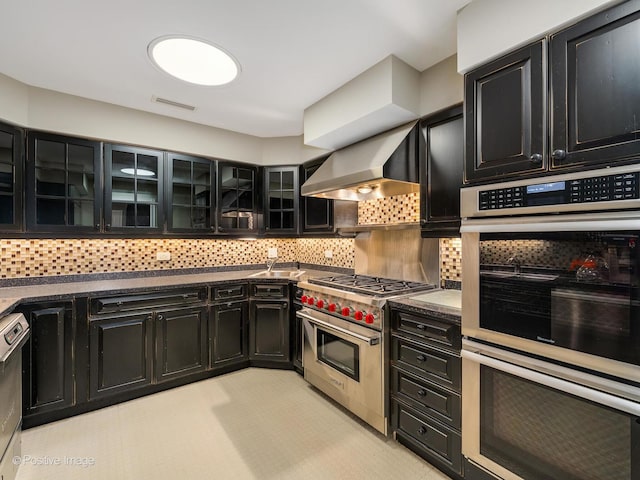 kitchen with decorative backsplash, visible vents, wall chimney exhaust hood, appliances with stainless steel finishes, and dark cabinets